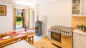 Eine kompakte Küche mit Einbauherd, kleinem Backofen und Essbereich mit Tisch für zwei Personen.