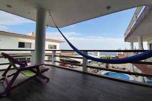 A balcony with a hammock, a pool, and a view of the cityscape. - Hotel Casa Mia (Puerto Escondido)