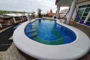 A swimming pool with a view of the sea and buildings in the background. - Hotel Casa Mia (Puerto Escondido)