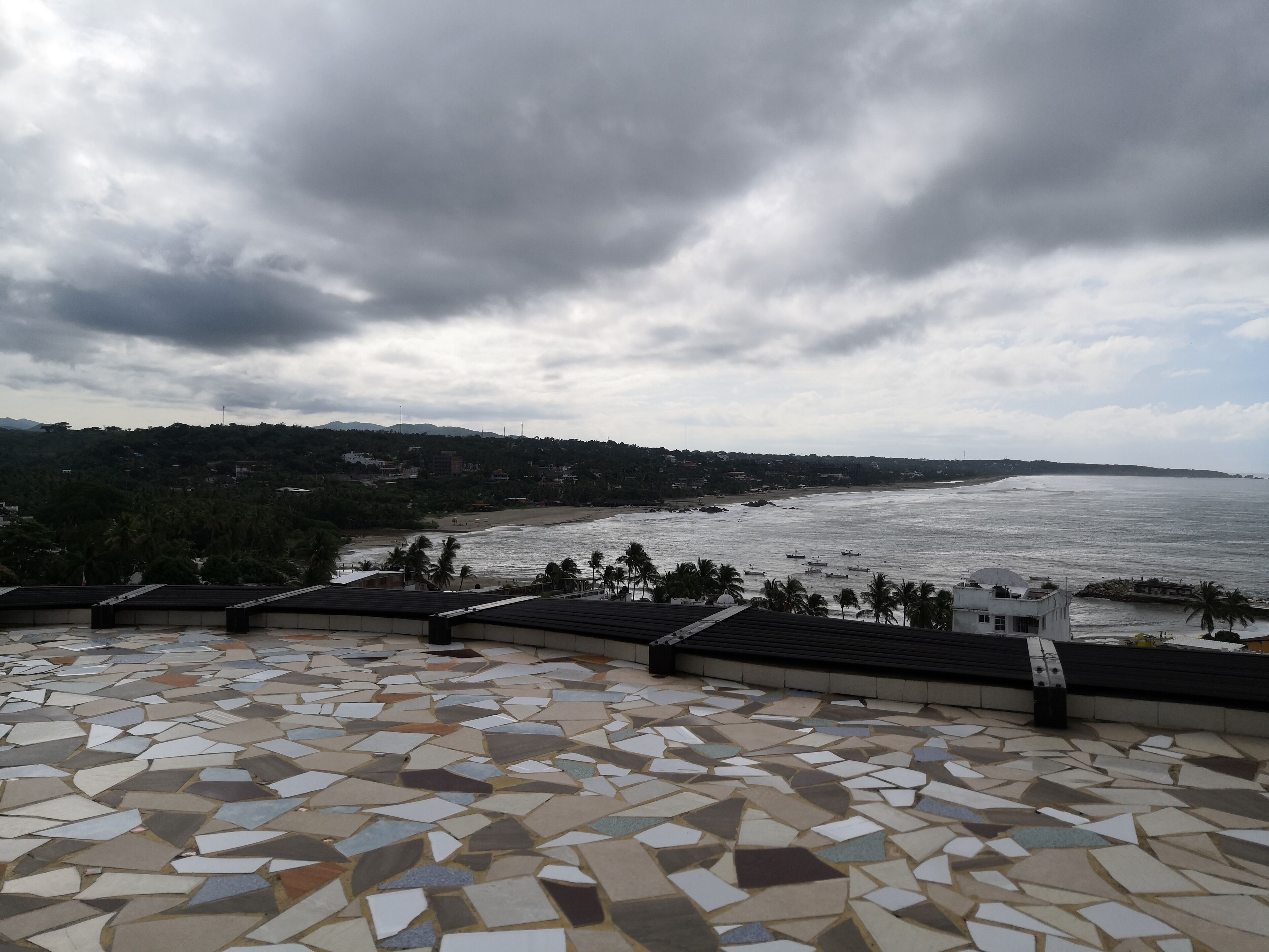 Una terraza con baldosas y vistas a una playa y al océano.