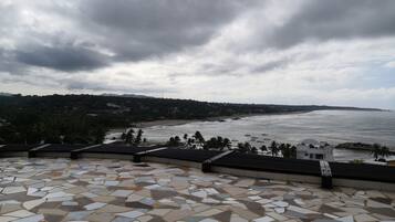 Una terraza con baldosas y vistas a una playa y al océano.