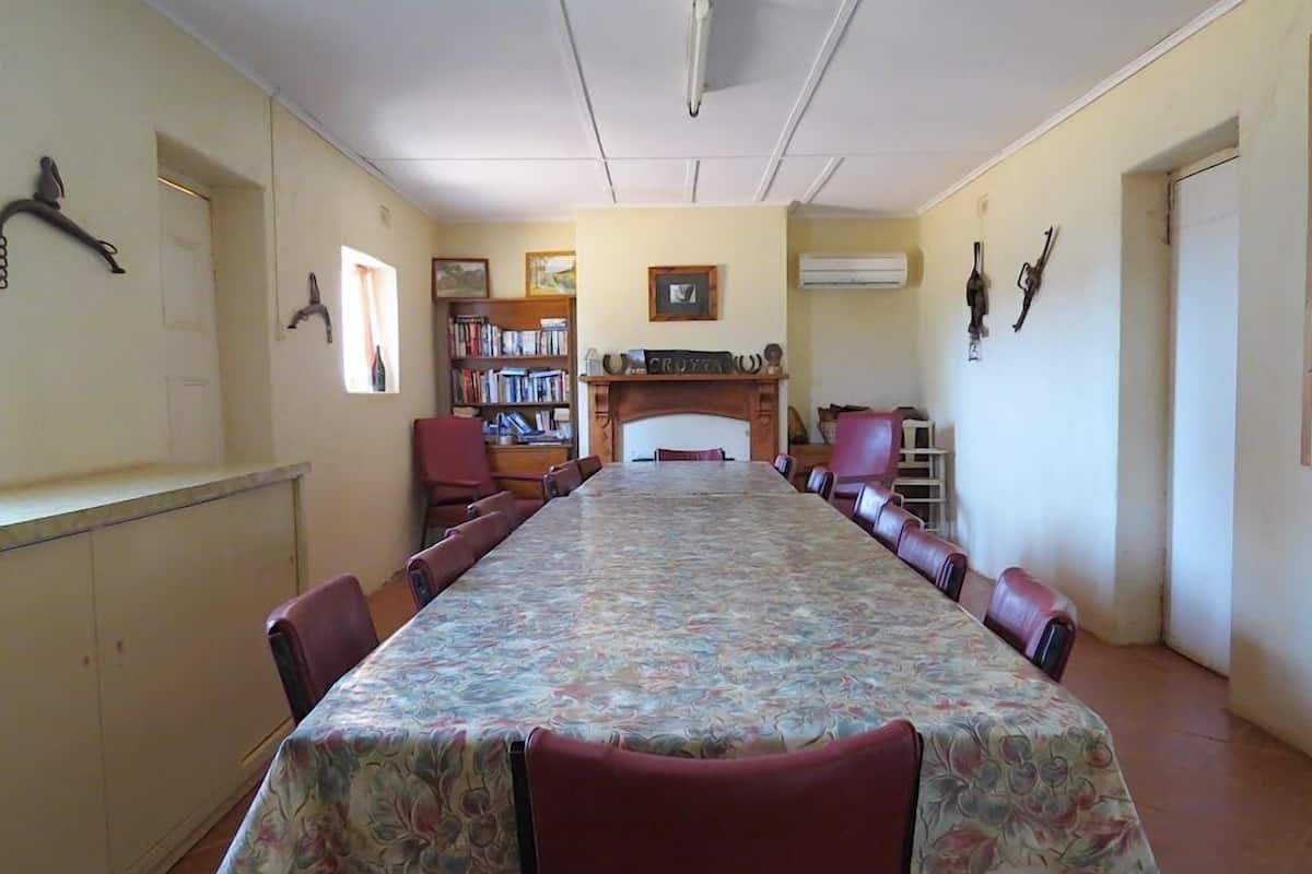 Un salón de conferencias con una larga mesa, sillas rojas, una chimenea y una estantería.