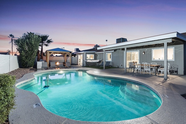 Backyard with large pool, sun loungers, covered patio with 6 person outdoor dining table, and a covered gazebo with bistro lights, outdoor furnishings, fire-pit, and BBQ.