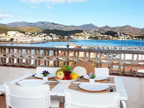 Mesa para dos con vista a un pueblo costero y montañas al fondo.