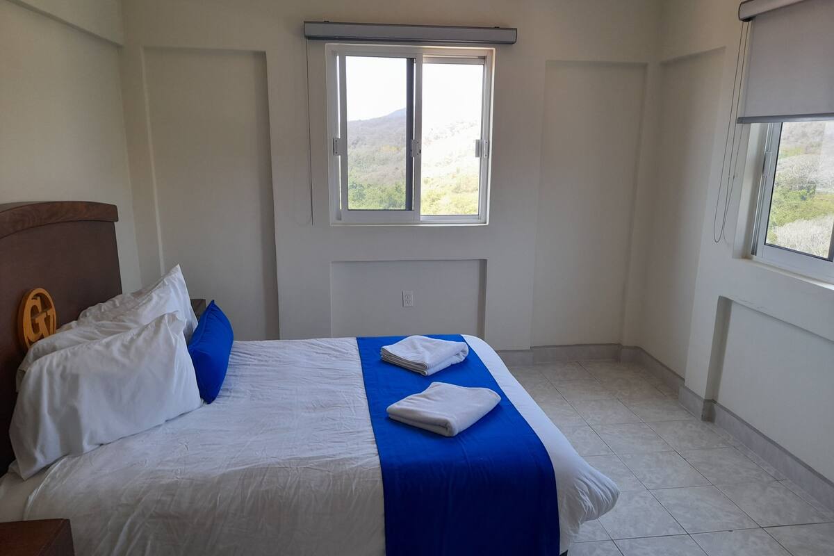 Una habitación de hotel con cama, ventana y vistas al exterior.