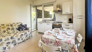 Een ruimtelijk ingerichte leefruimte met kitchenette, eethoek en een zithoek.