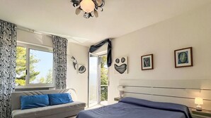 Een slaapkamer met een groot bed, een bank en een balkon met gordijnen.