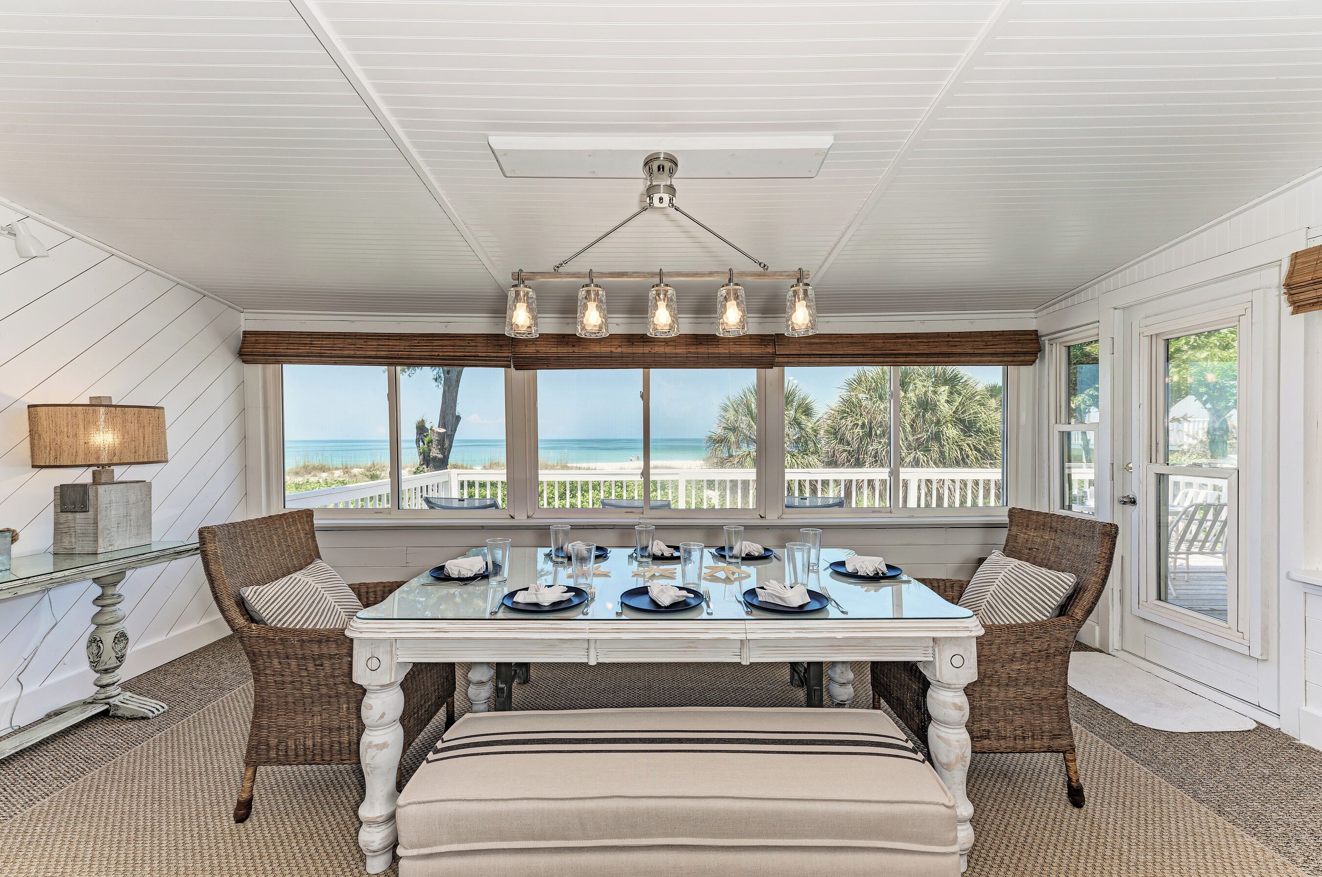 Un coin repas avec une table dressée pour six personnes, donnant sur une plage.