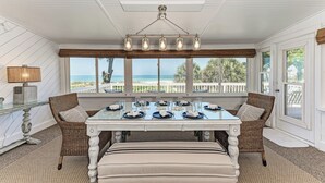 Comedor con una mesa dispuesta para seis personas, con vista a la playa.