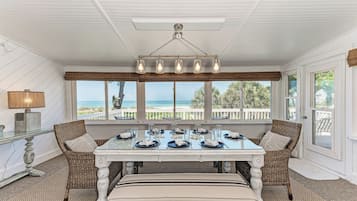 Un coin repas avec une table dressée pour six personnes, donnant sur une plage.