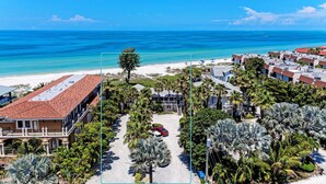 Un hotel costero con techo de tejas rojas, palmeras y vistas al océano.