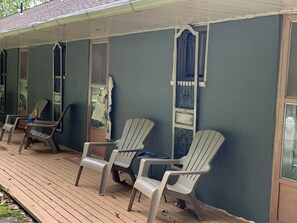 A covered porch with several Adirondack chairs, a wooden deck, and a blue exterior wall. - Cabin-like Studio Motel Suite (Big Indian)