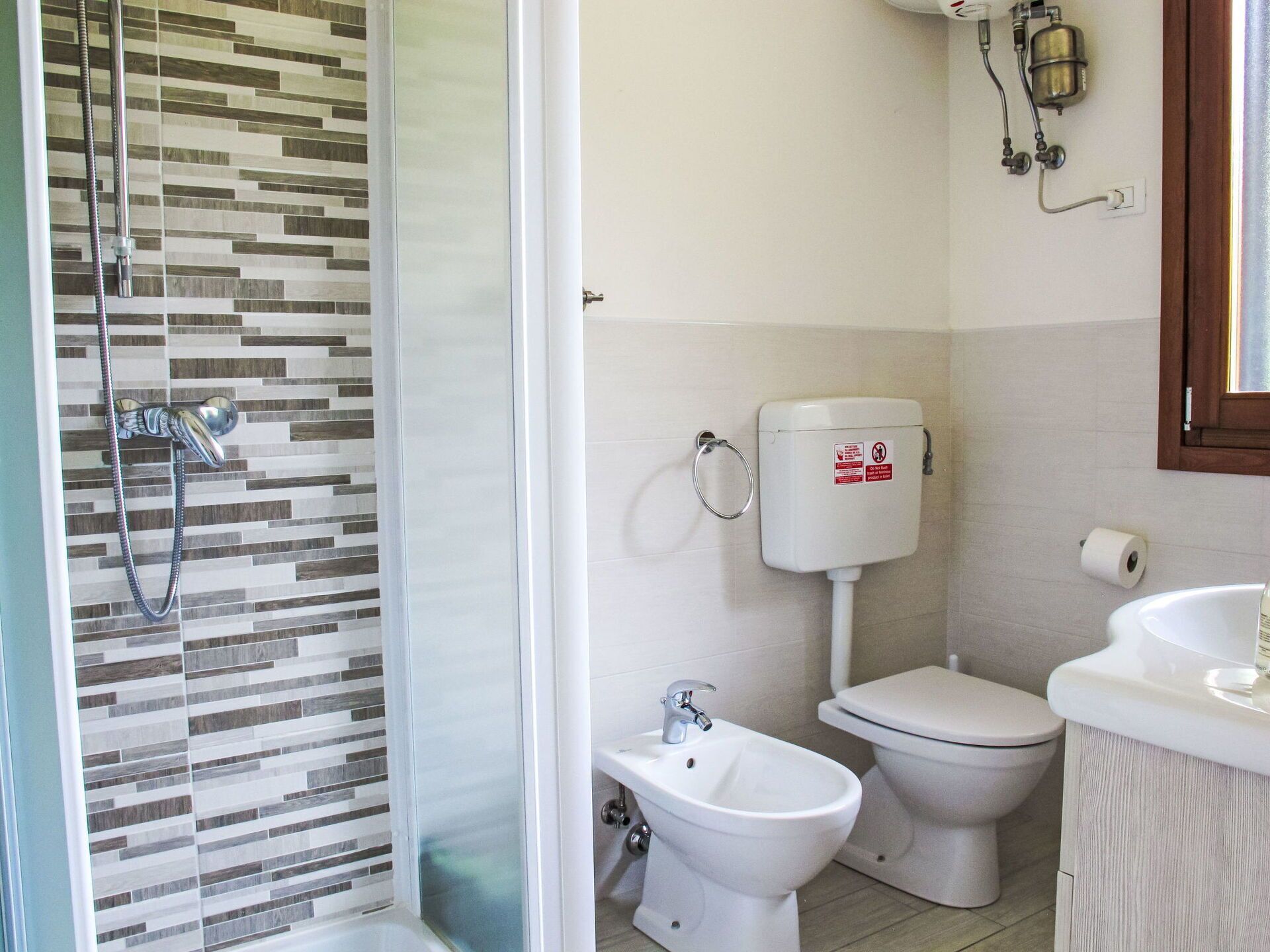 Une salle de bain équipée d’une douche, de toilettes, d’un bidet et d’un lavabo.