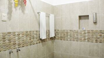 Un baño con azulejos color beige, un perchero y un secador de manos.
