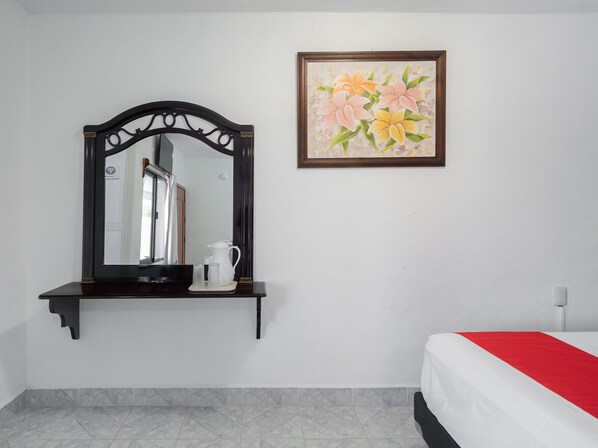 A hotel room with a bed, a bedside table with a white pitcher, and a framed floral painting on the wall. - Hotel Casa Poblana (Bacalar)