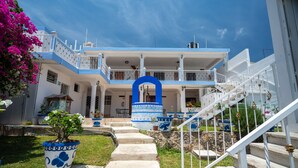 A two-story building with a blue and white color scheme, a central archway, and a staircase leading to the upper floor. - Hotel Casa Poblana (Bacalar)