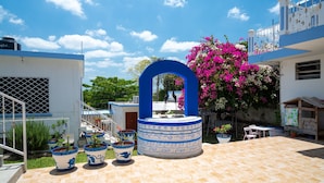 A courtyard with a fountain, potted plants, and a staircase leading to a balcony. - Hotel Casa Poblana (Bacalar)