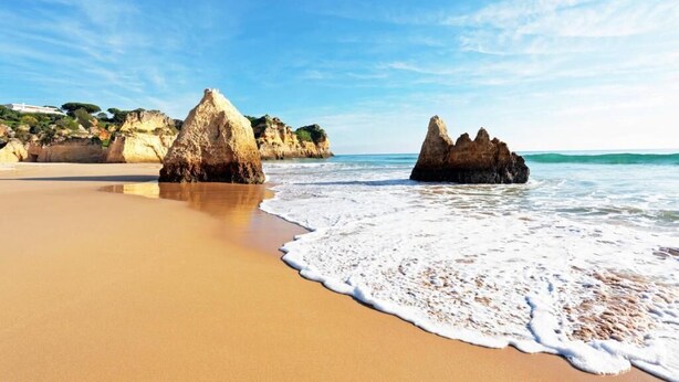 A beach with clear skies, calm waves, and rocky formations. - Villa Maria I (Alvor)