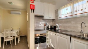 Una cucina con mobili bianchi, un lavello in acciaio inossidabile e un orologio appeso al muro.