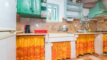 Une cuisine avec des meubles de couleur verte, un pare-feu en carrelage et des rideaux à motifs jaunes.