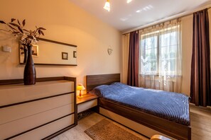 Ein Schlafzimmer mit Bett, Nachttisch, Lampe und einer Vase mit Blumen.