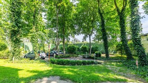 Un camino pavimentado que conduce a un espacio verde con árboles y un banco.