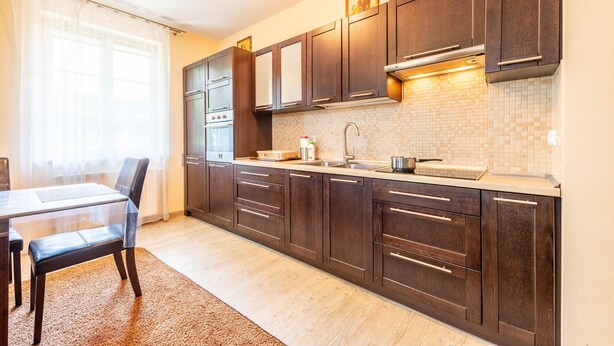 Una cocina moderna con armarios de madera oscura, salpicadero de azulejos y un lavamanos de acero inoxidable.