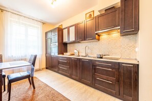 Una cocina moderna con armarios de madera oscura, salpicadero de azulejos y un lavamanos de acero inoxidable.