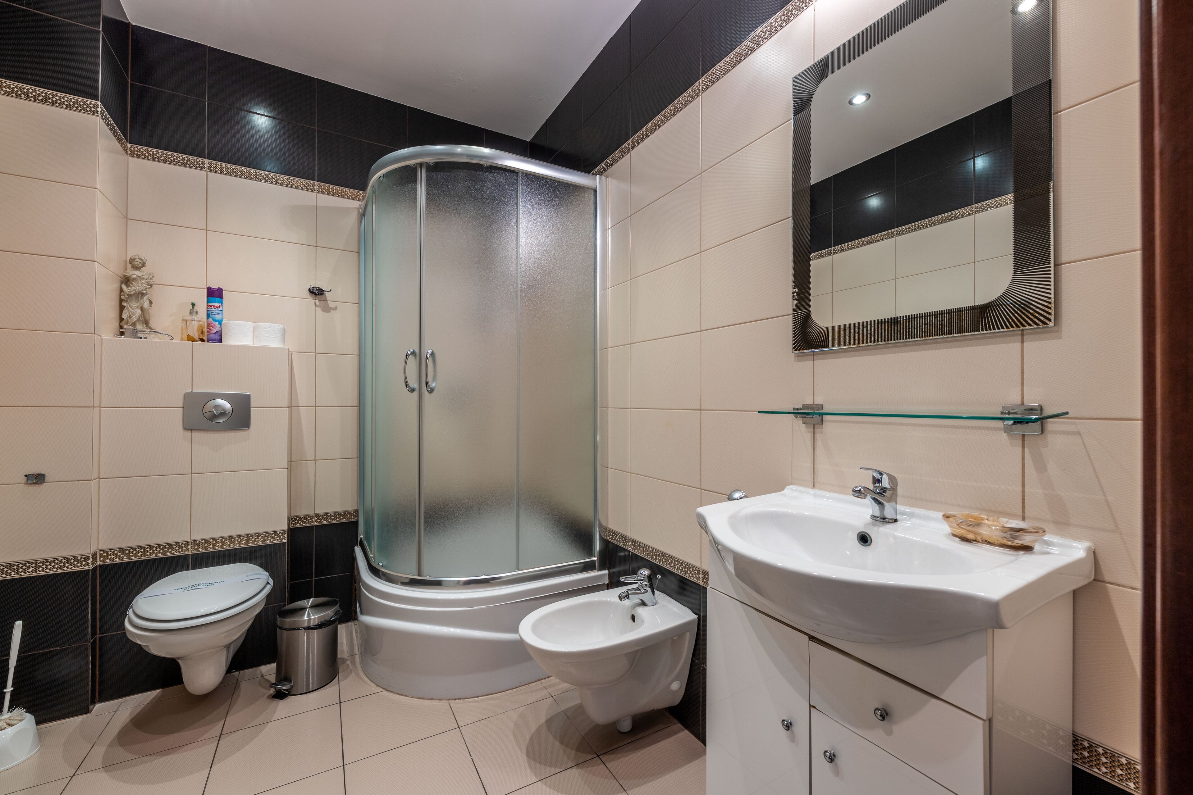 A modern bathroom with a glass-enclosed shower, a white sink, and a bidet.