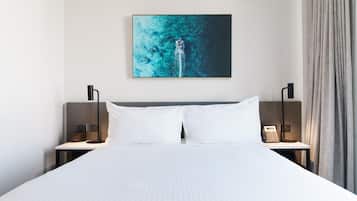 Una habitación de hotel con una cama grande, dos mesitas de noche, una obra de arte colgada y un teléfono.