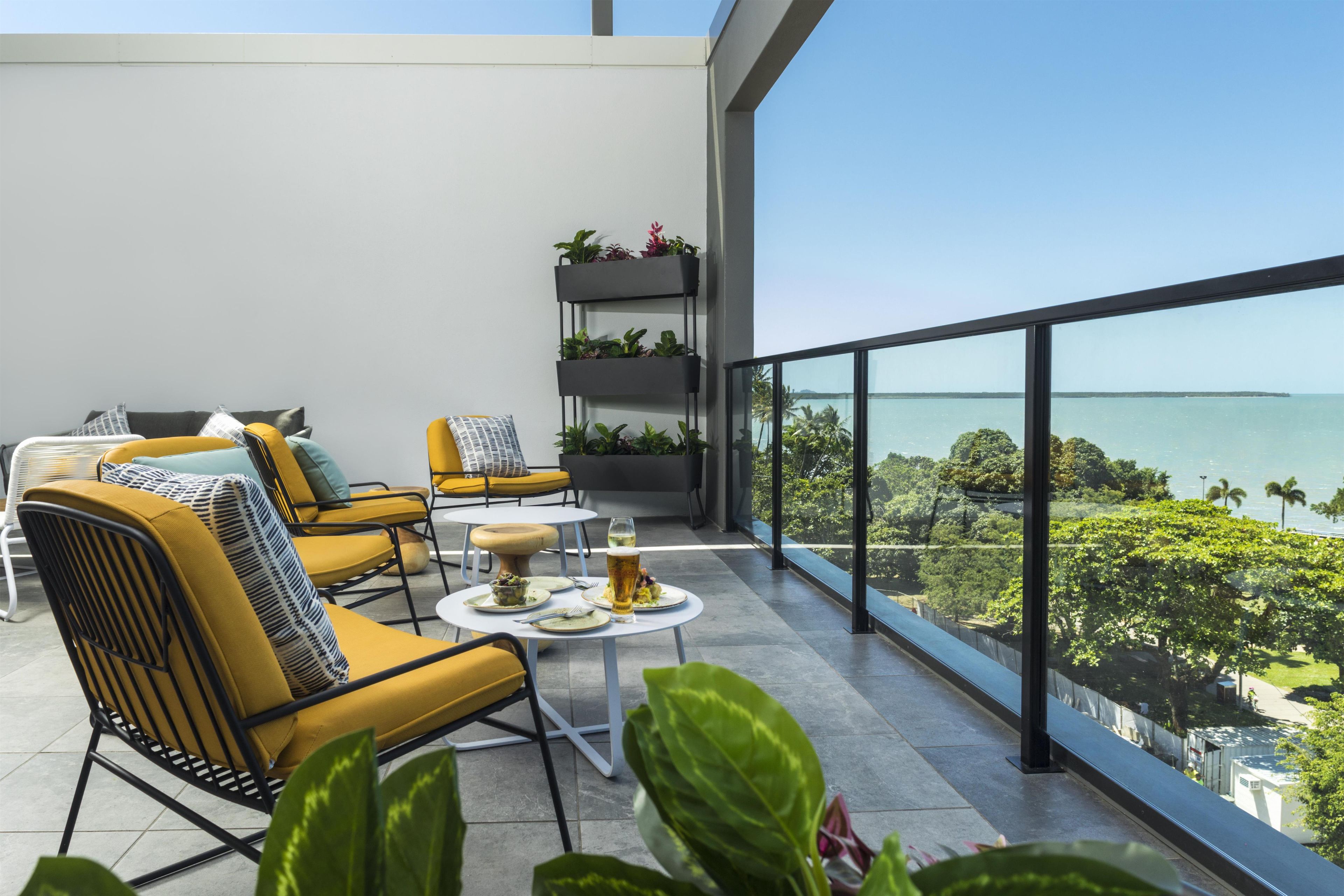 Un balcon avec des chaises jaunes, une petite table et un pot de fleurs.