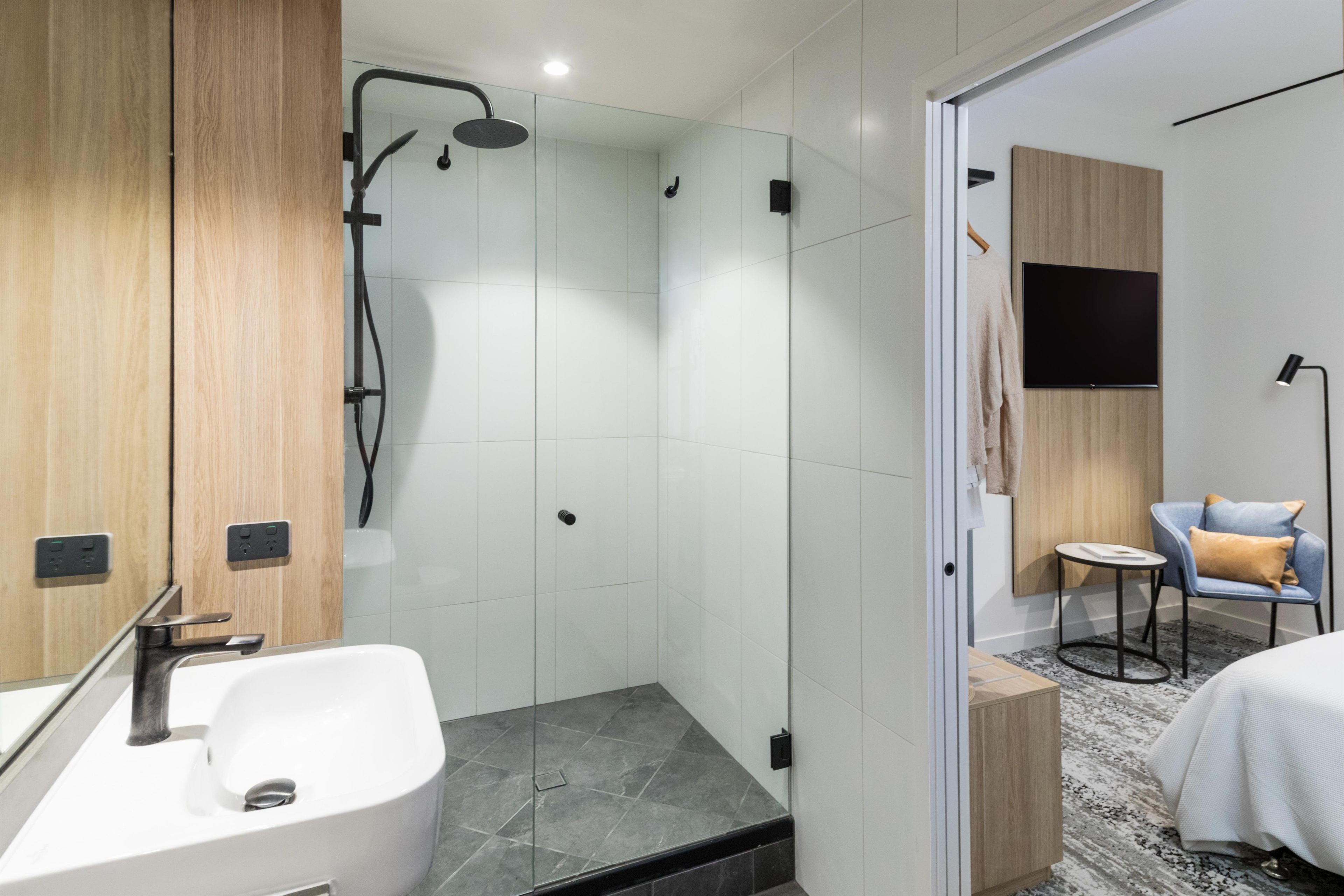 A modern bathroom with a shower, a sink, and a mirror.