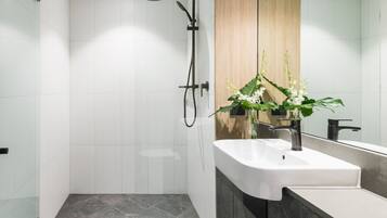 A modern bathroom with a glass shower enclosure, a wooden vanity, and a white sink.