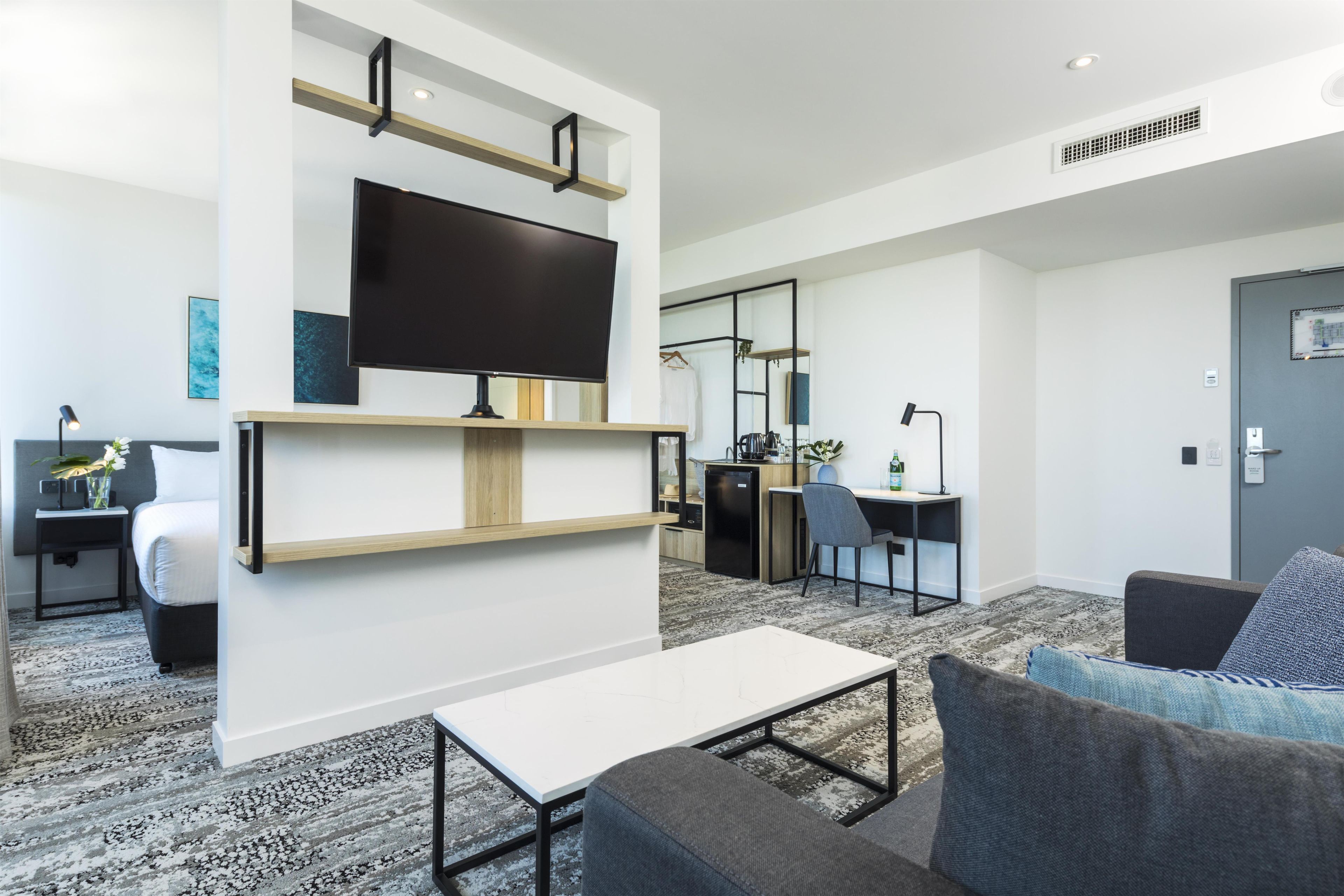 A modern living room with a flat-screen TV, a coffee table, and a sofa.
