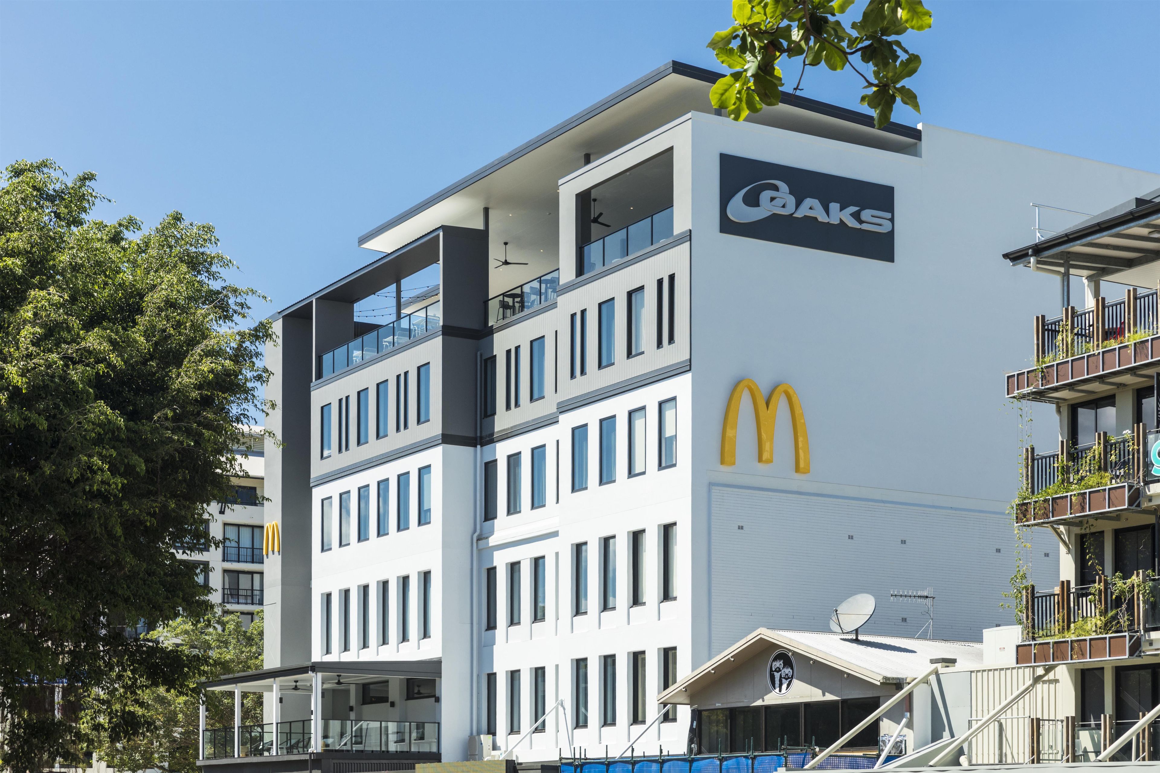 Ein modernes Gebäude mit McDonald's Logo und einem Coaks Schild, das mehrere Balkone und große Fenster aufweist.
