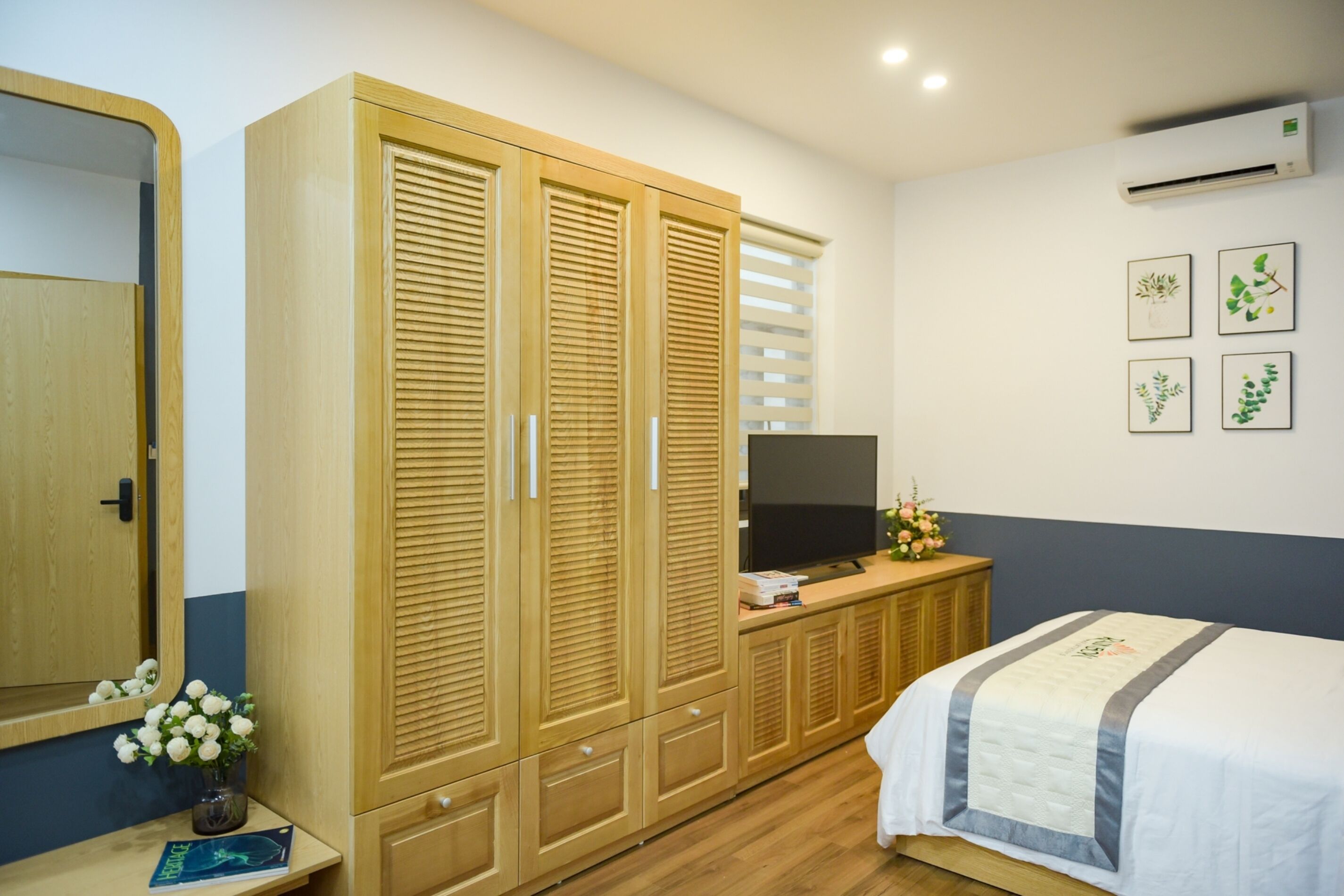 Un dormitorio con cama, armario de madera, televisor y decoración en la pared.