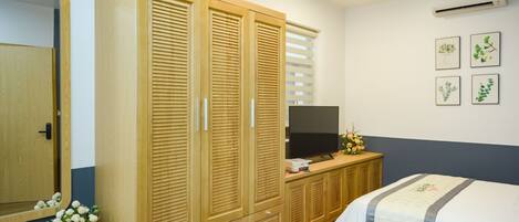 Un dormitorio con cama, armario de madera, televisor y decoración en la pared.