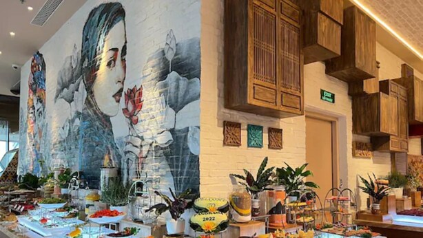 A buffet with various food items and a large mural on the wall. - Rainbow Apartment Hai Phong (Hai Phong)