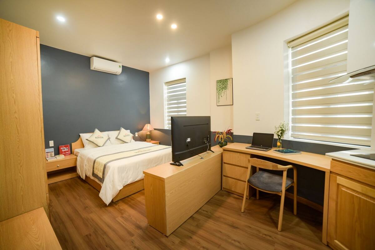 A compact hotel room with a bed, desk, chair, and a small table.