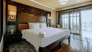 A large bed with a wooden headboard, two bedside lamps, and a rolled towel on the bed. - Rainbow Apartment Hai Phong (Hai Phong)
