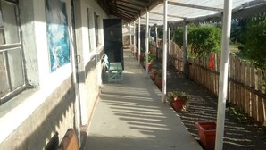 A covered outdoor area with a bench, potted plants, and a wooden fence. - Firebird Inn (Naivasha)