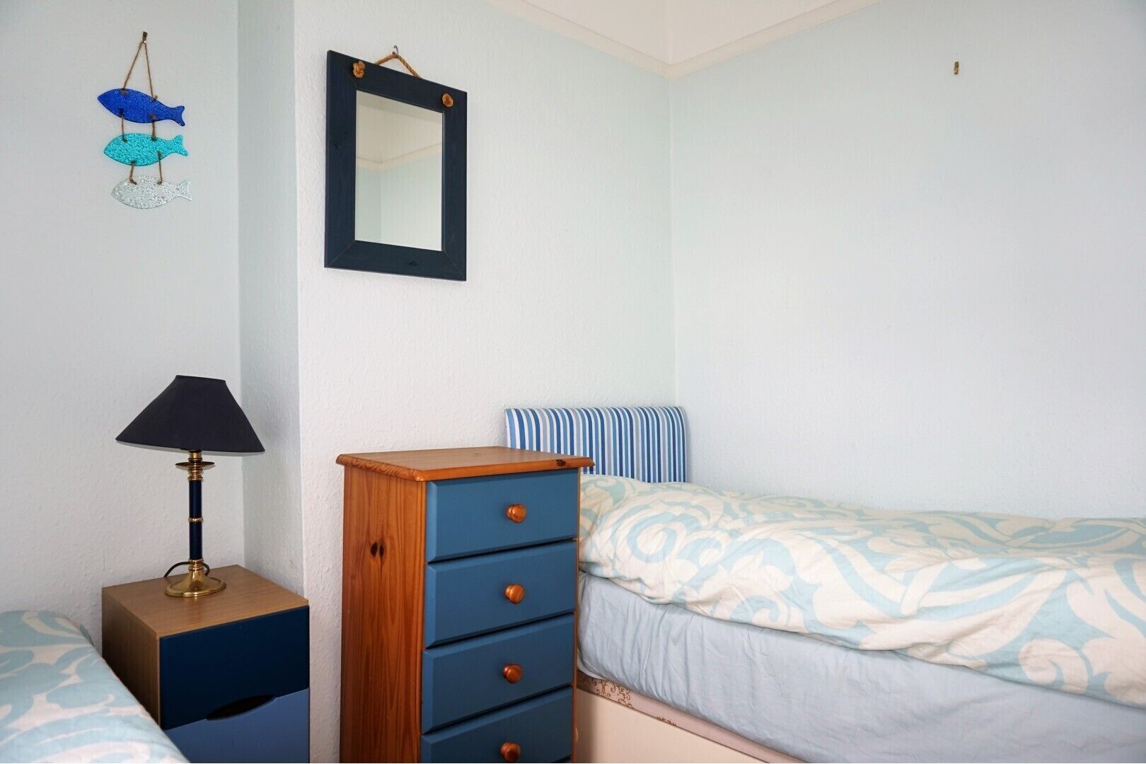 A bedroom with a bed, a dresser, a nightstand, a lamp, and a mirror.