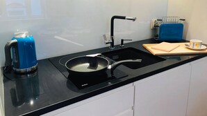 A modern kitchen with a black countertop, a sink, a kettle, and a toaster.