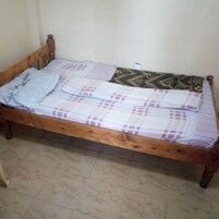 Una cama de madera individual con una colcha estampada y una almohada con texto.