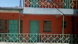 A multi-story building with green shutters and a balcony with a geometric railing. - Jordan Guest House (Mai Mahiu)