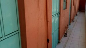 A corridor with teal doors and orange walls, leading to a room with a tiled floor. - Jordan Guest House (Mai Mahiu)