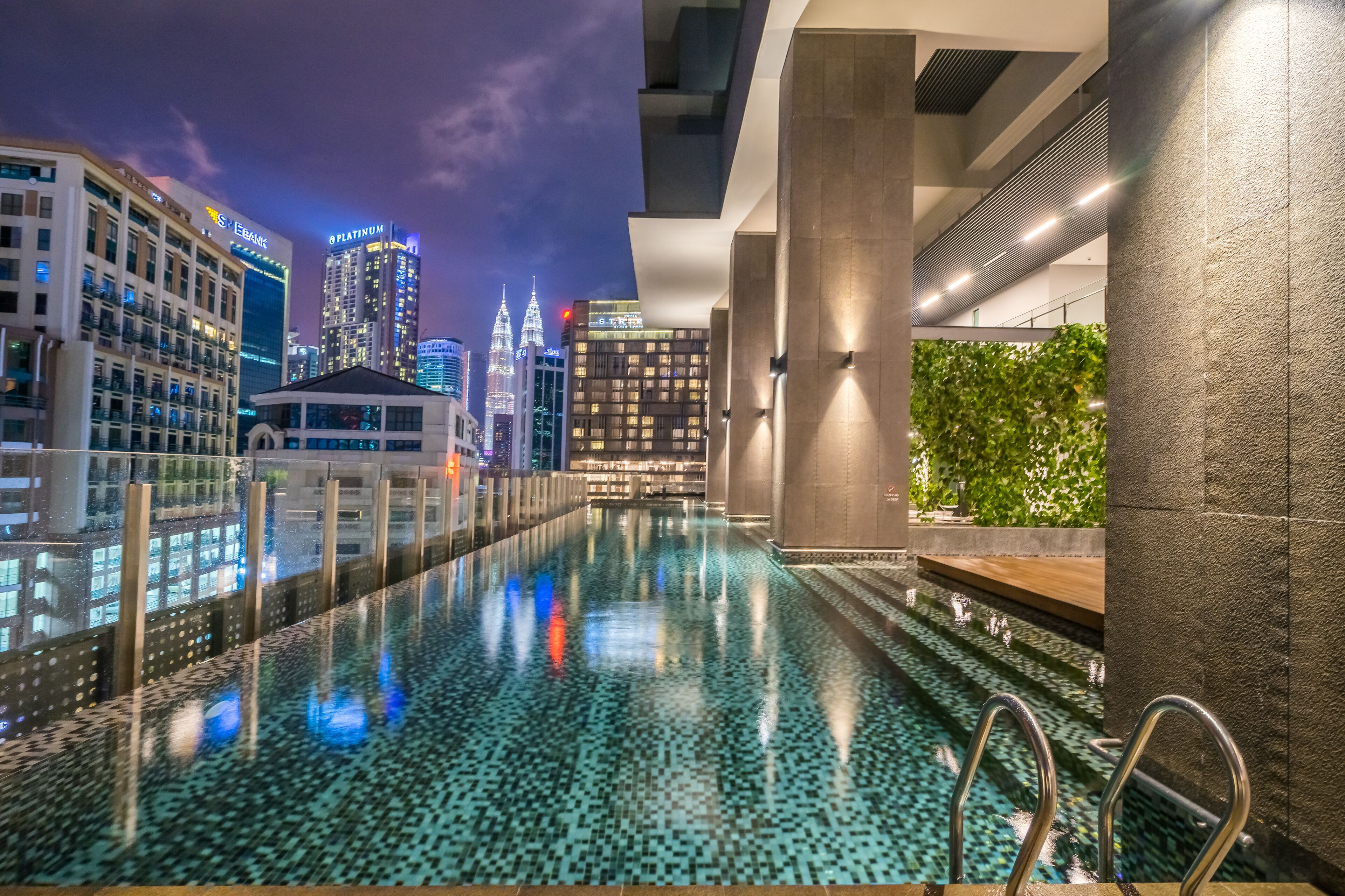 Piscina moderna de hotel con vista al horizonte de la ciudad, incluyendo edificios destacados como E. banc y PLATINUM.