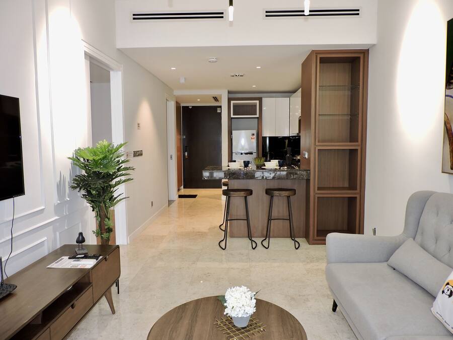Una sala de estar moderna con un sofá, una mesa de centro con un jarrón, un televisor, un escritorio y una planta.
