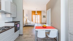 Une cuisine moderne dotée d’un îlot central, de meubles blancs et d’un coin repas avec une nappe rouge.
