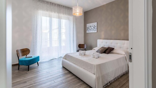 Une chambre avec un grand lit, une chaise et un luminaire suspendu.